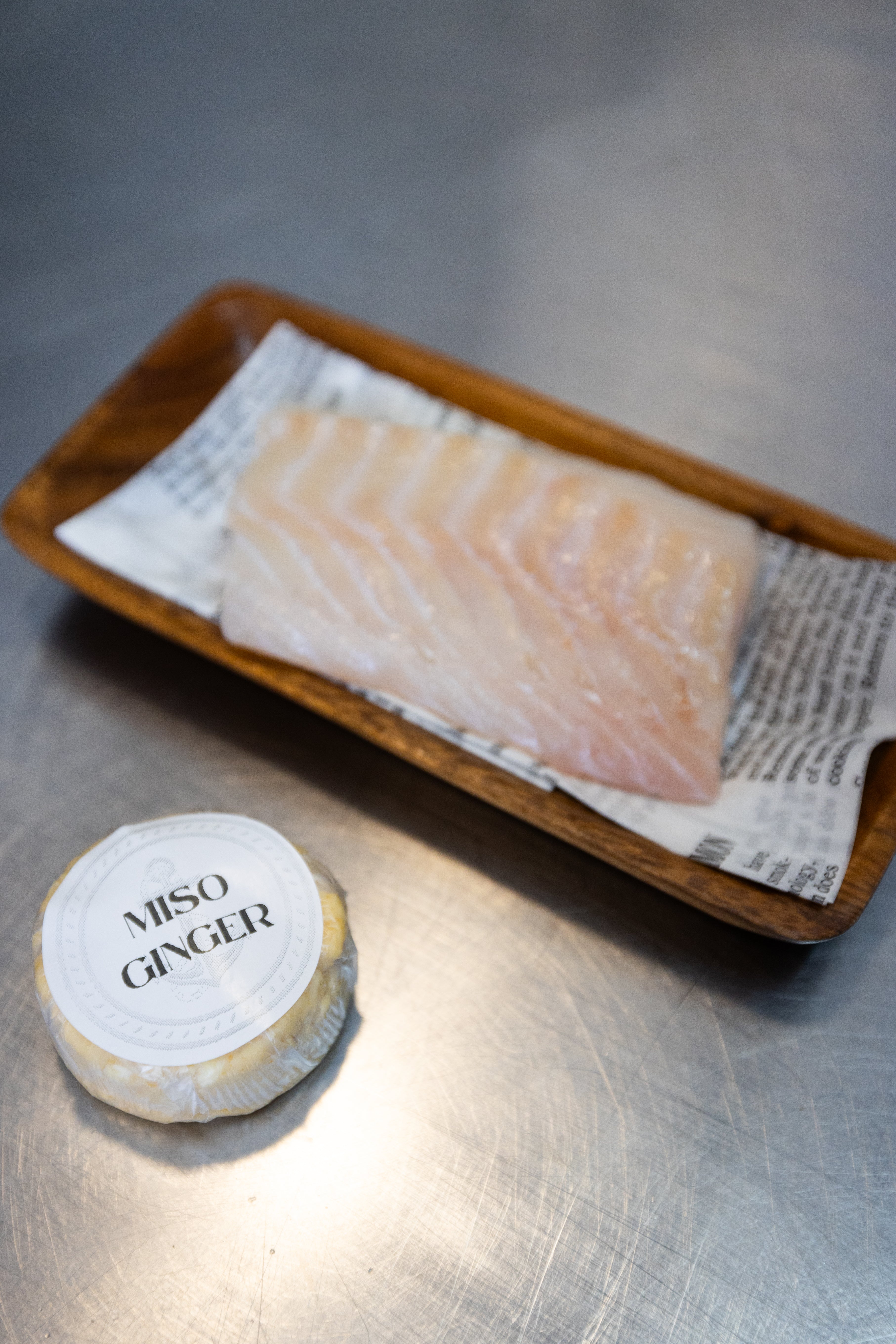 A piece of fish next to a puck of miso ginger butter