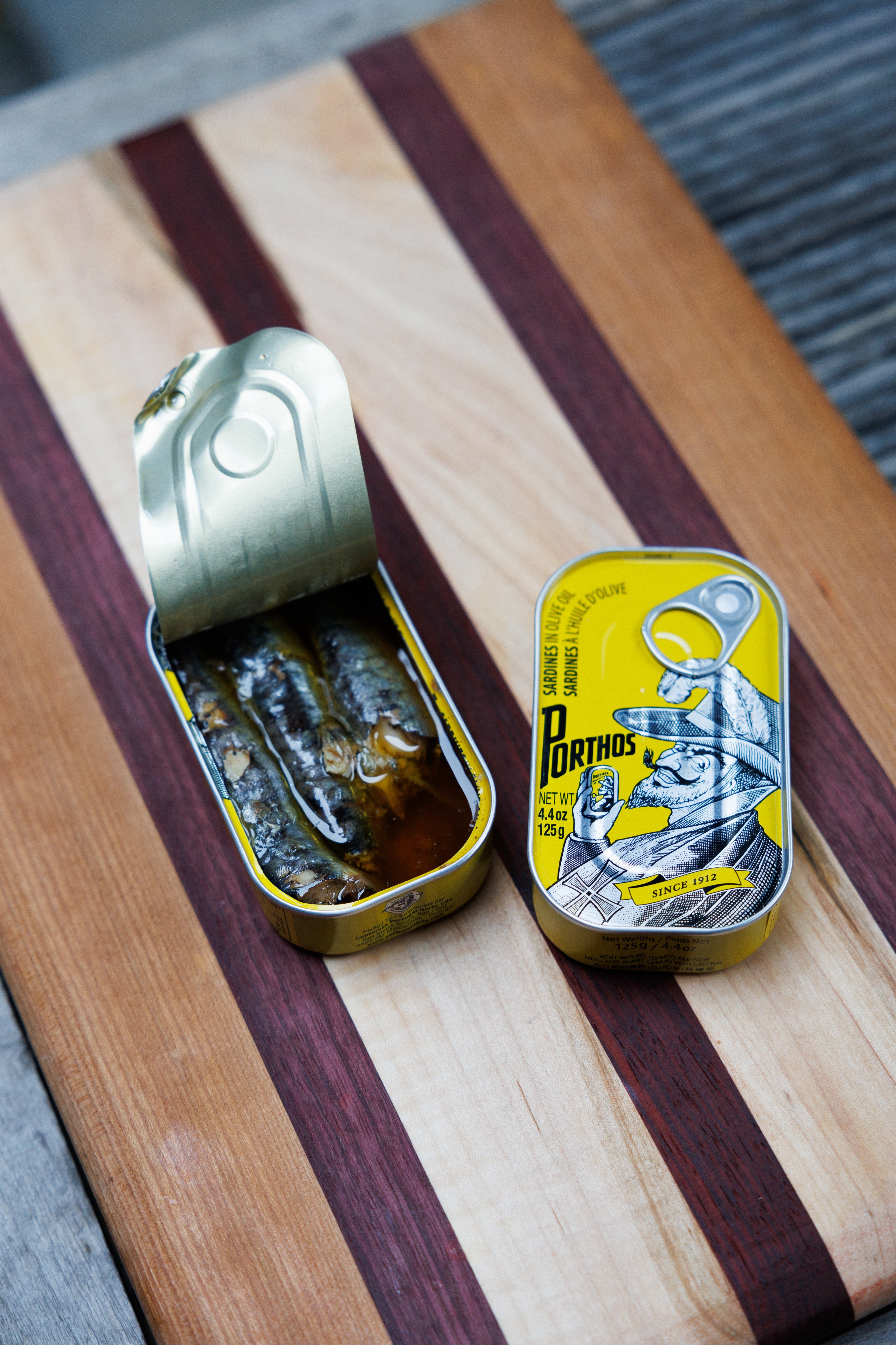 Opened and unopened tins of Porthos sardines in olive oil.